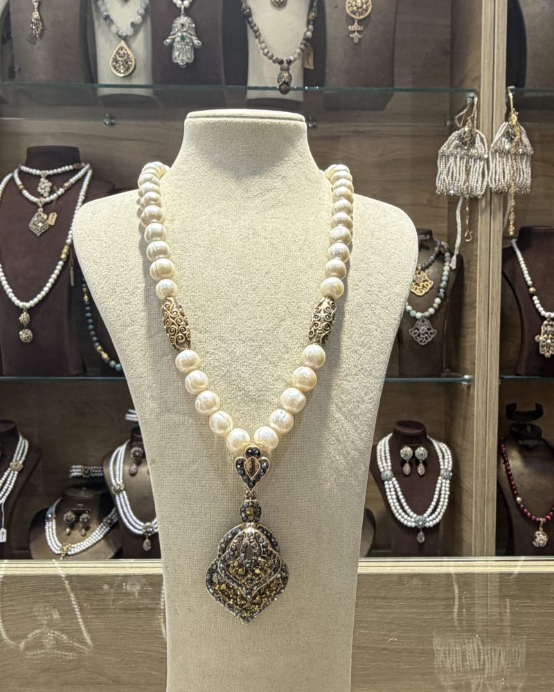 Collier Pique noir traditionnel algérien en grandes perles de culture avec intercalaires barils dorés et pendentif en pique inversée orné de cristaux noirs et dorés,