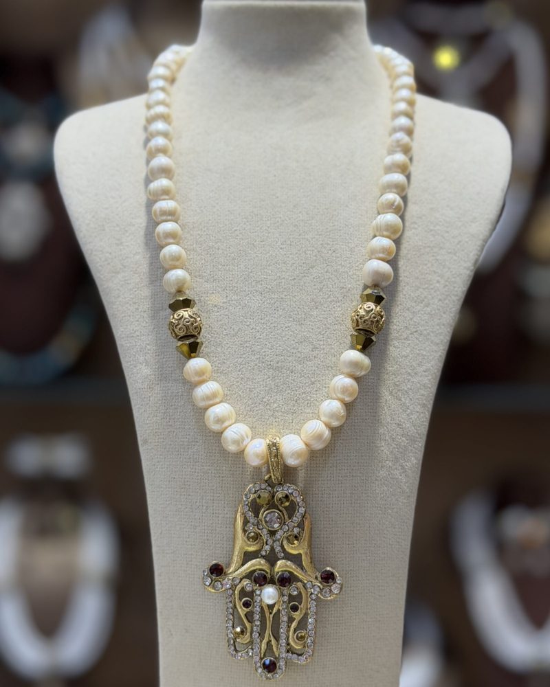Collier Khamssa en perles de culture avec pendentif Main de Fatma doré serti de cristaux et pierres décoratives.