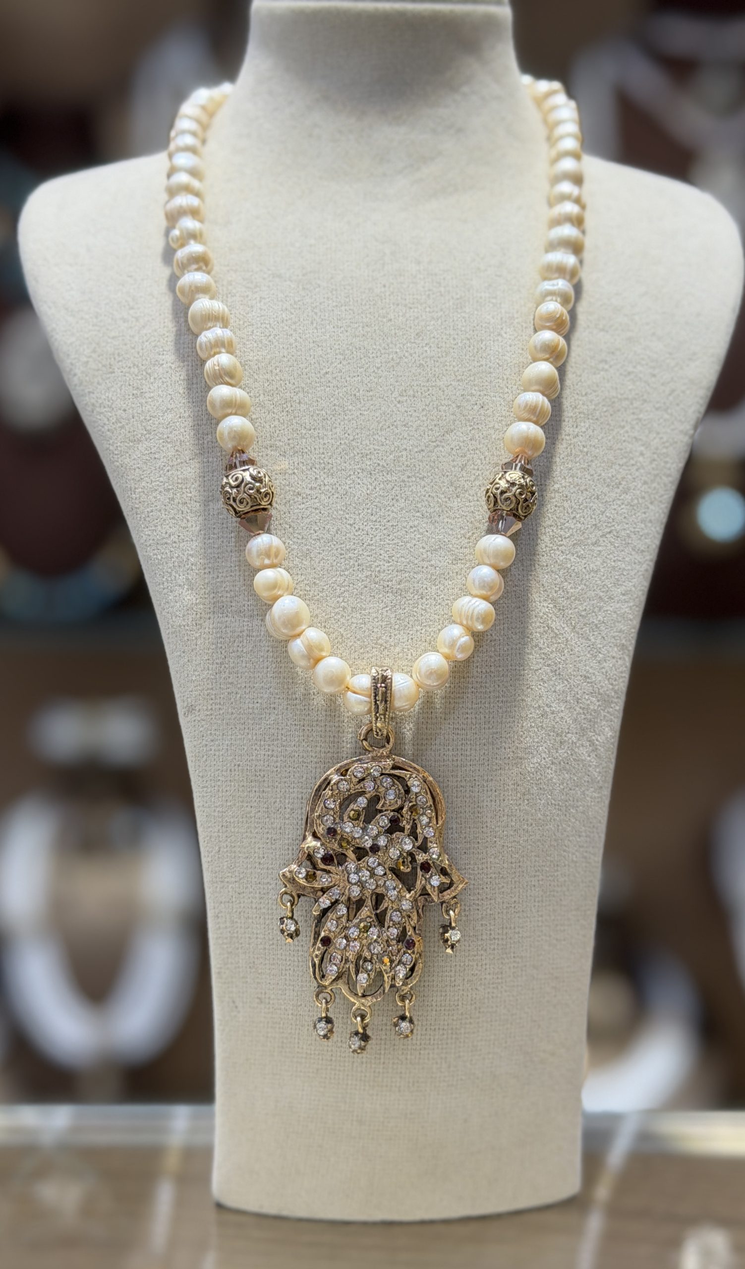 collier lalla jasmine Collier Main de Fatma Lalla Jasmine en perles de culture avec pendentif Khamssa doré, cristaux scintillants et breloques mobiles inspirés de la joaillerie algérienne.