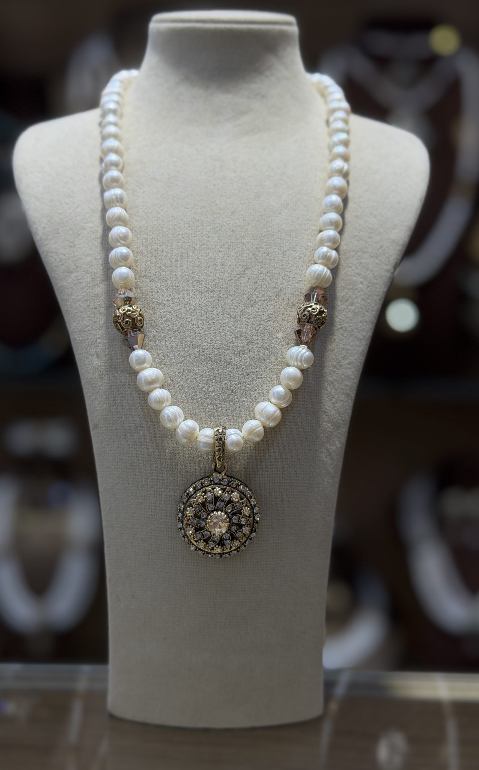 collier louiza1 Collier Louiza traditionnel algérien en véritables perles de culture baroques blanches avec un grand pendentif médaillon circulaire en filigrane d'or et cristaux scintillants, présenté sur un buste