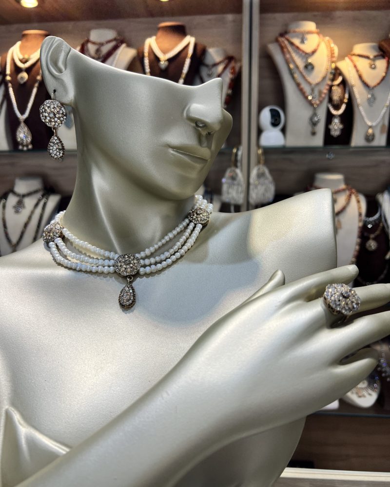 Parure perles culture Zerrouf comprenant un collier ras-du-cou à trois rangs, des boucles d'oreilles pendantes et une bague en bronze doré ciselé avec cristaux miels