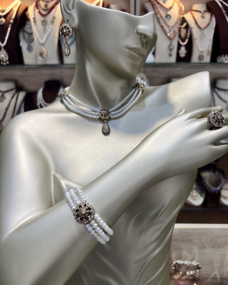 Parure perles bordeaux Zerrouf comprenant un collier ras-du-cou, un bracelet multi-rangs, des boucles d'oreilles pendantes et une bague en bronze doré ciselé avec cristaux bordeaux