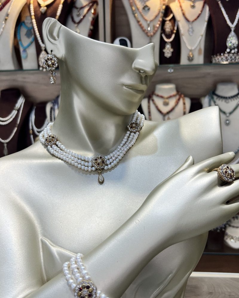 Parure perles bordeaux or Zerrouf comprenant un collier ras-du-cou à trois rangs, un bracelet, des boucles d'oreilles et une bague fleur en bronze traité à l'or avec cristaux bordeaux