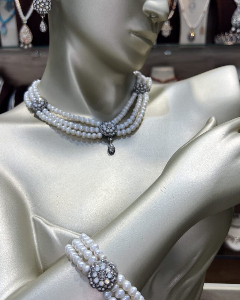 Parure perles blanches Zerrouf avec collier ras-du-cou, bracelet à trois rangs et boucles d'oreilles en bronze traité à l'or avec cristaux clairs et blancs