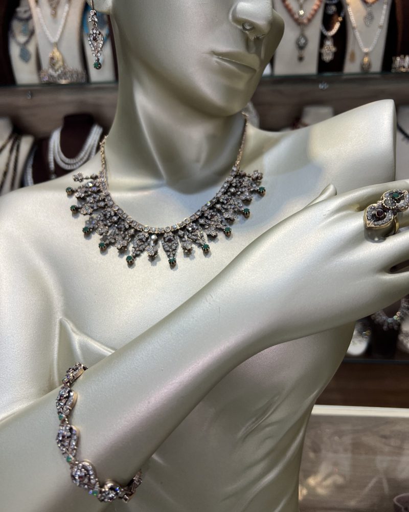 Parure Lalla Farihene comprenant un collier plastron, un bracelet, des boucles d'oreilles et une bague en bronze doré avec cristaux clairs, verts et bordeaux