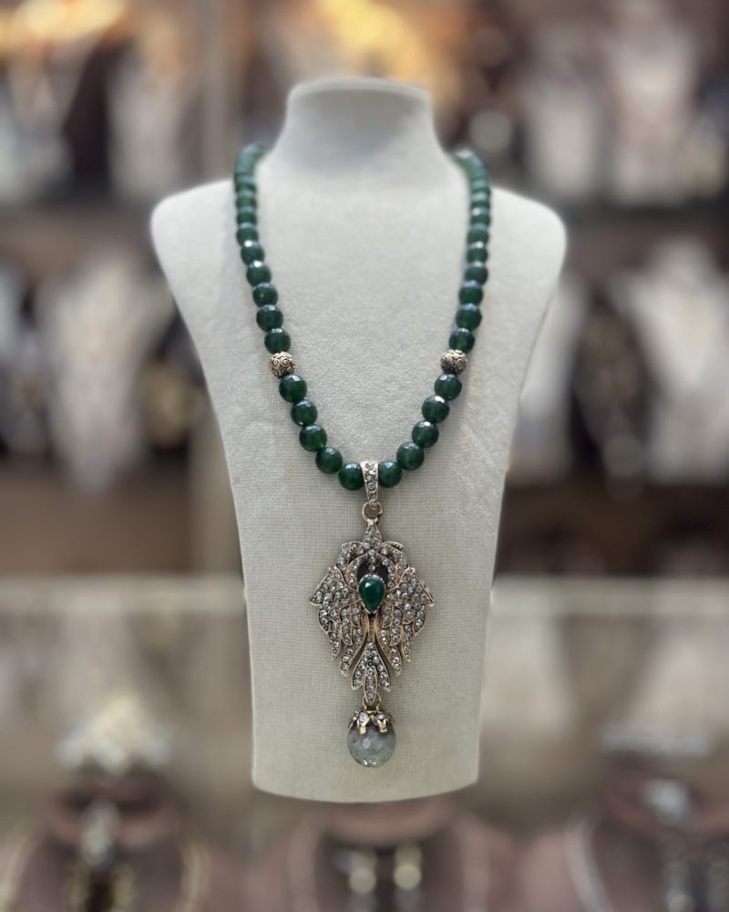Collier Élisabeth en perles naturelles vertes avec intermédiaires dorés et somptueux pendentif ajouré serti de cristaux avec pierre centrale verte