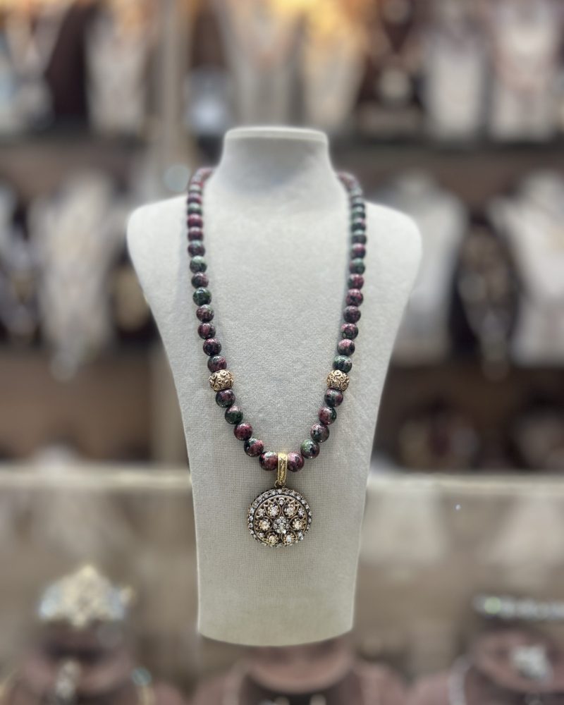 Collier Louisa en perles naturelles aux nuances vertes et bordeaux avec intermédiaires dorés et pendentif rond serti de cristaux