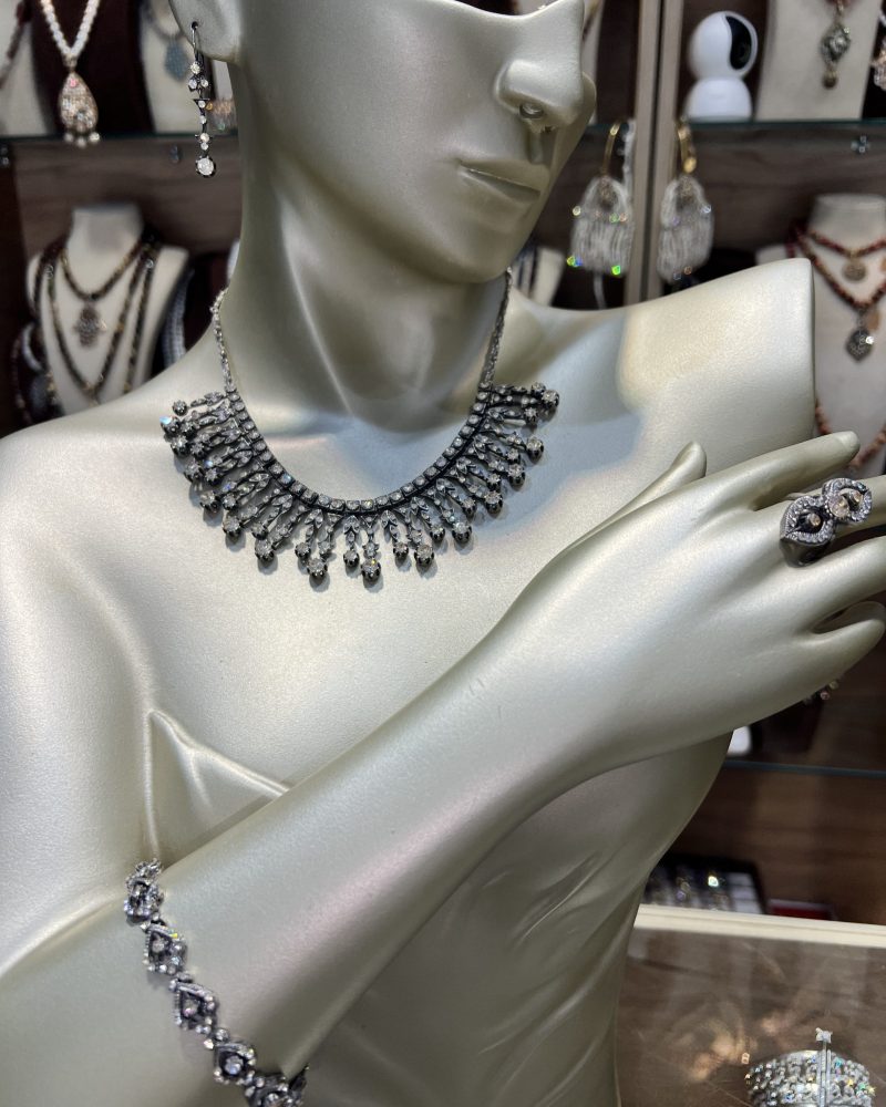 Parure Lalla Manel argentée 4 pièces comprenant un collier à pampilles, un bracelet articulé, des boucles d'oreilles et une bague en bronze finition argent vieilli et cristaux clairs