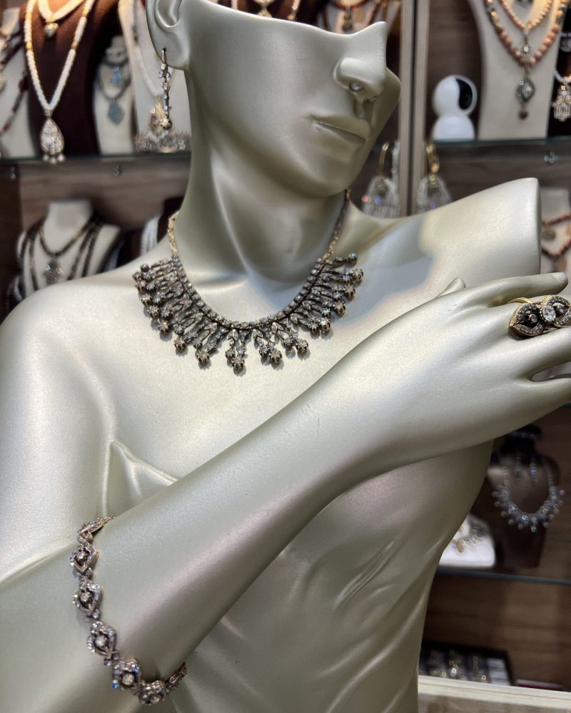 Parure Lalla Manel dorée 4 pièces comprenant un collier en pampilles feuillagées, un bracelet fin, des boucles d'oreilles et une bague en bronze traité à l'or et cristaux clairs