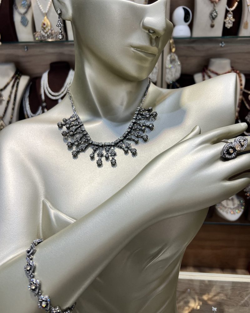 Parure Lalla Soraya argentée 4 pièces comprenant un collier draperie, un bracelet fin, des boucles d'oreilles et une bague en bronze finition argent vieilli et cristaux clairs