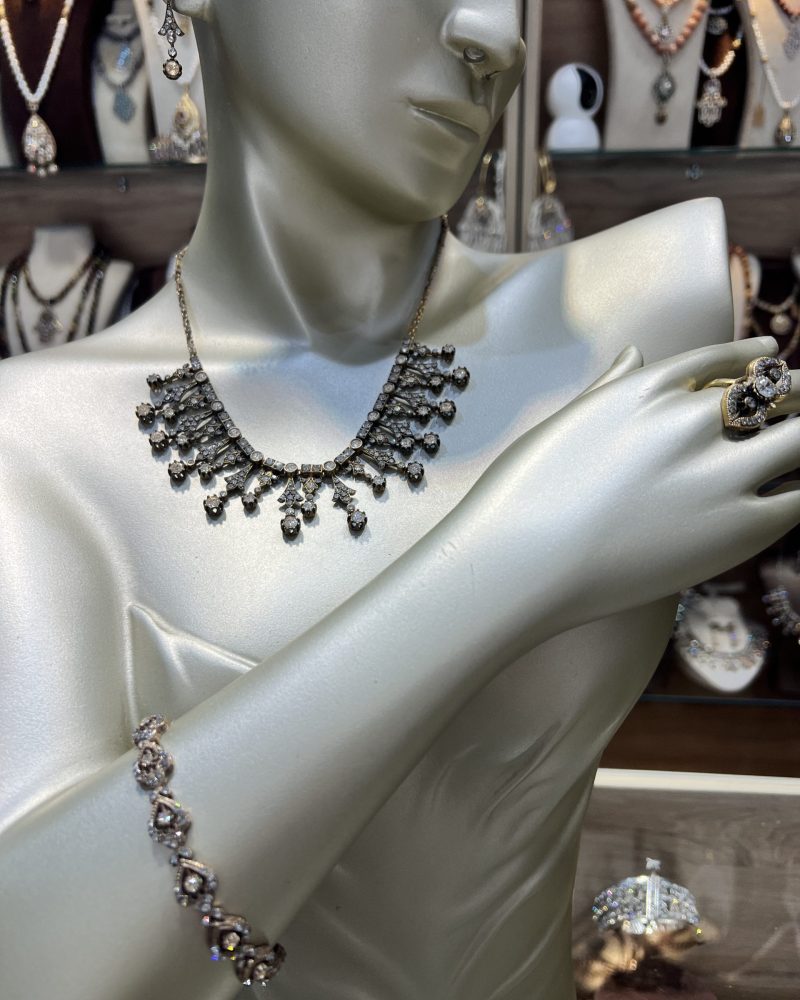 Parure Lalla Soraya dorée 4 pièces comprenant un collier draperie, un bracelet fin, des boucles d'oreilles et une bague en bronze traité à l'or et cristaux clairs