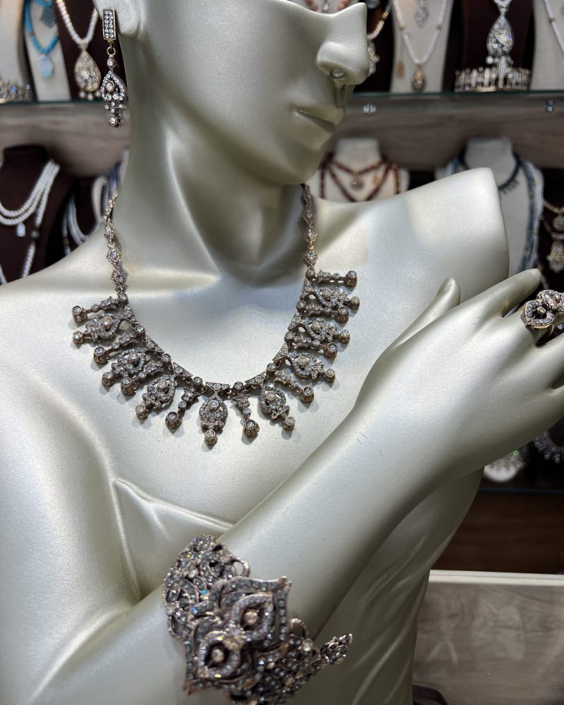 Parure Victoria 4 pièces comprenant un collier draperie, un bracelet manchette, des boucles d'oreilles et une bague en bronze traité à l'or avec cristaux clairs et miels.
