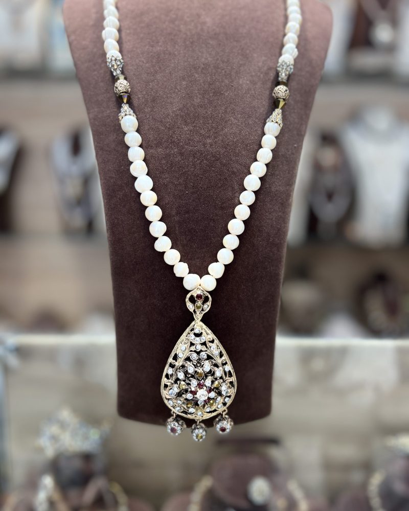 Sautoir El Meskia Royale en Djoher El Hor perles véritables avec intermédiaires dorés travaillés et pendentif goutte serti de cristaux bordeaux et dorés
