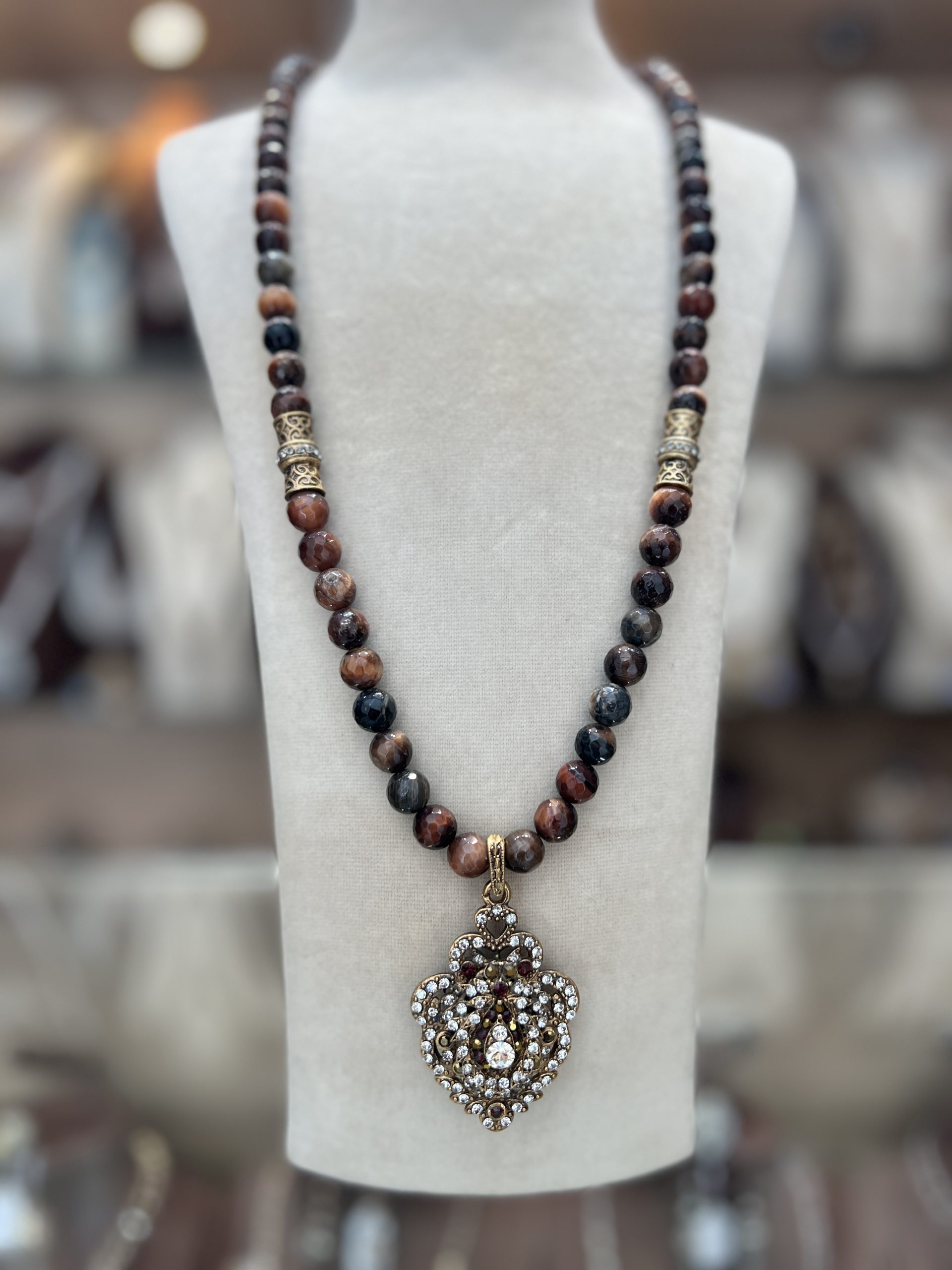 sautoir-cleo-perles-d-agathe Sautoir Cléo Perles D'Agathe en pierres facettées sombres et œil-de-tigre avec cylindres ciselés en bronze doré et pendentif cœur blason pavé de zircons,