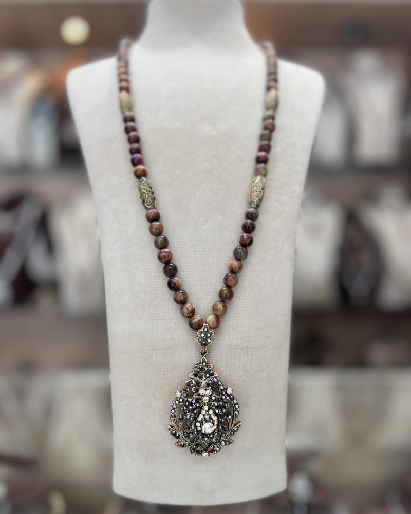 Sautoir Cléo Hématite en perles texturées prune et bois de rose avec olives dorées gravées de volutes et grand pendentif ajouré serti de cristaux sombres