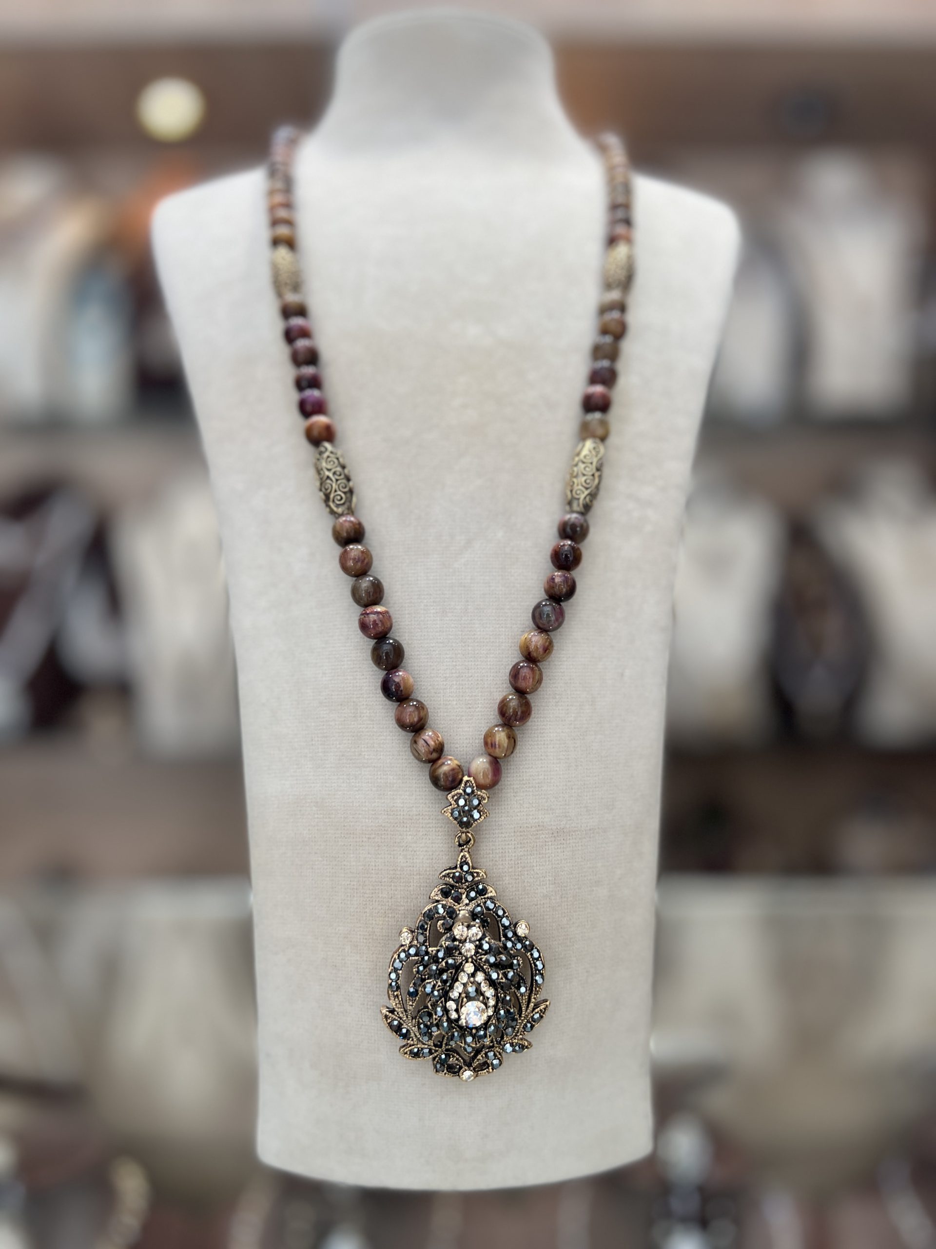 sautoir-cleo-hematite Sautoir Cléo Hématite en perles texturées prune et bois de rose avec olives dorées gravées de volutes et grand pendentif ajouré serti de cristaux sombres