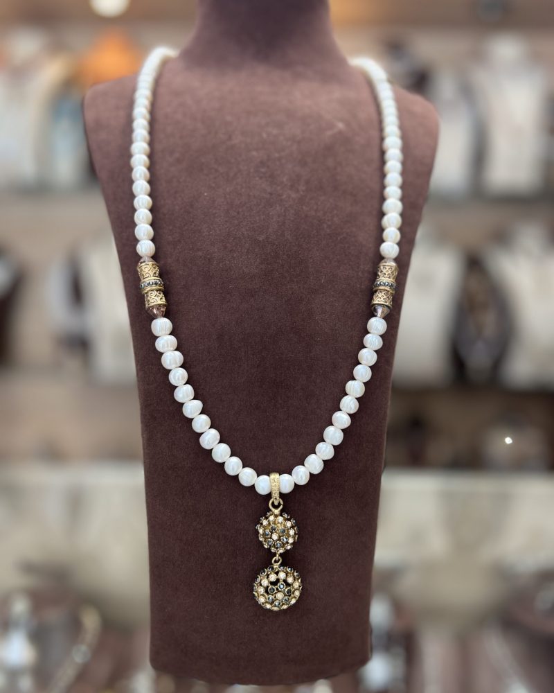 Sautoir Hérisson Pierre Noire Hématite en perles El Djohar nacrées blanches avec cylindres dorés ciselés et pendentif double sphère incrusté de zircons
