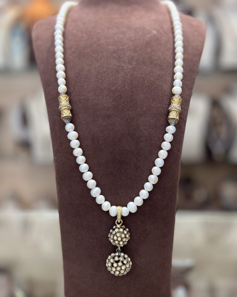 Sautoir Hérisson en perles El Djohar nacrées blanches avec cylindres dorés ciselés, cristaux transparents et pendentif double sphère serti de zircons clairs