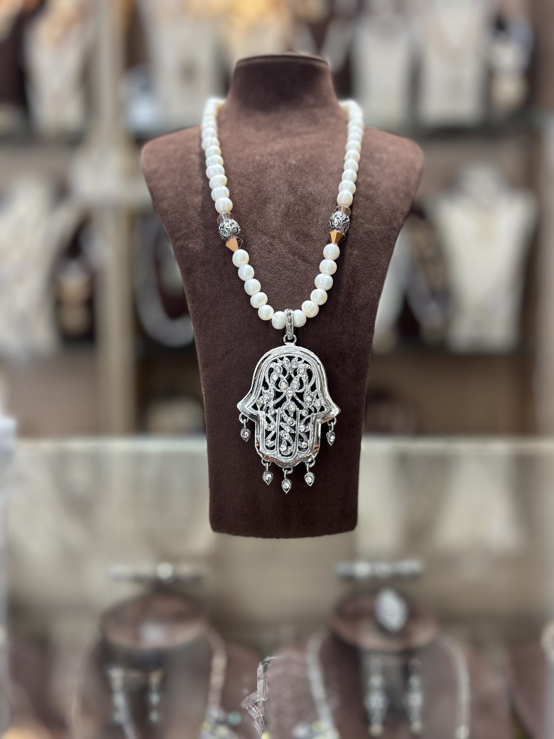 sautoir-khamssa-argente-perles-nacrees Sautoir en perles nacrées blanches avec intermédiaires argentés et grand pendentif Khamssa ajouré serti de zircons et pampilles