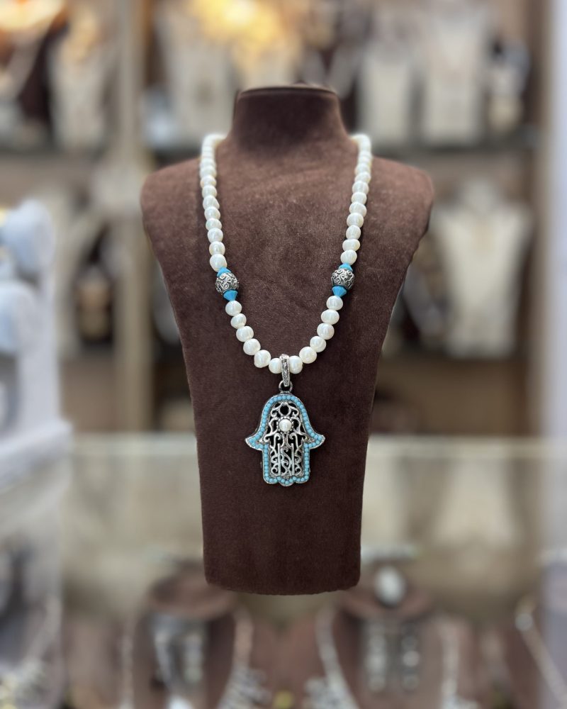Sautoir en perles nacrées blanches avec intermédiaires argentés, perles turquoise et grand pendentif Khamssa bordé de pierres turquoise