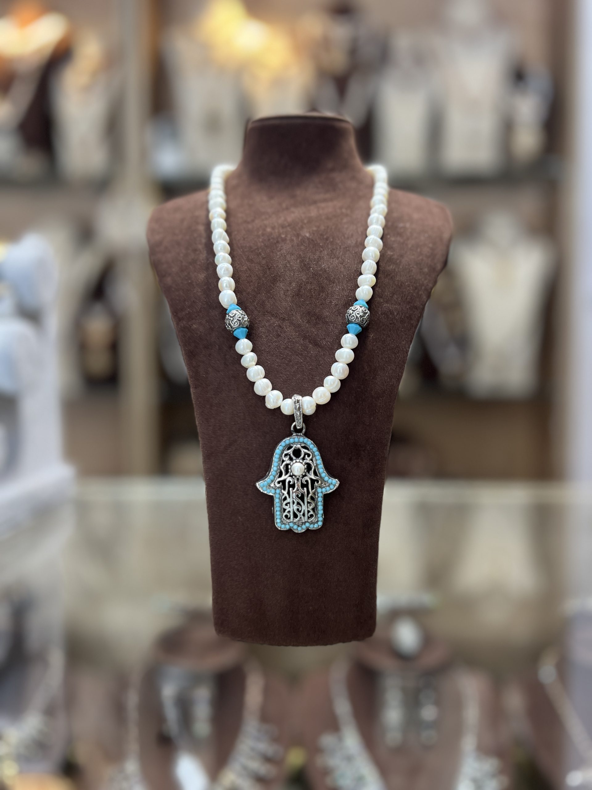 sautoir-khamssa-d-azur-perles-nacrees Sautoir en perles nacrées blanches avec intermédiaires argentés, perles turquoise et grand pendentif Khamssa bordé de pierres turquoise