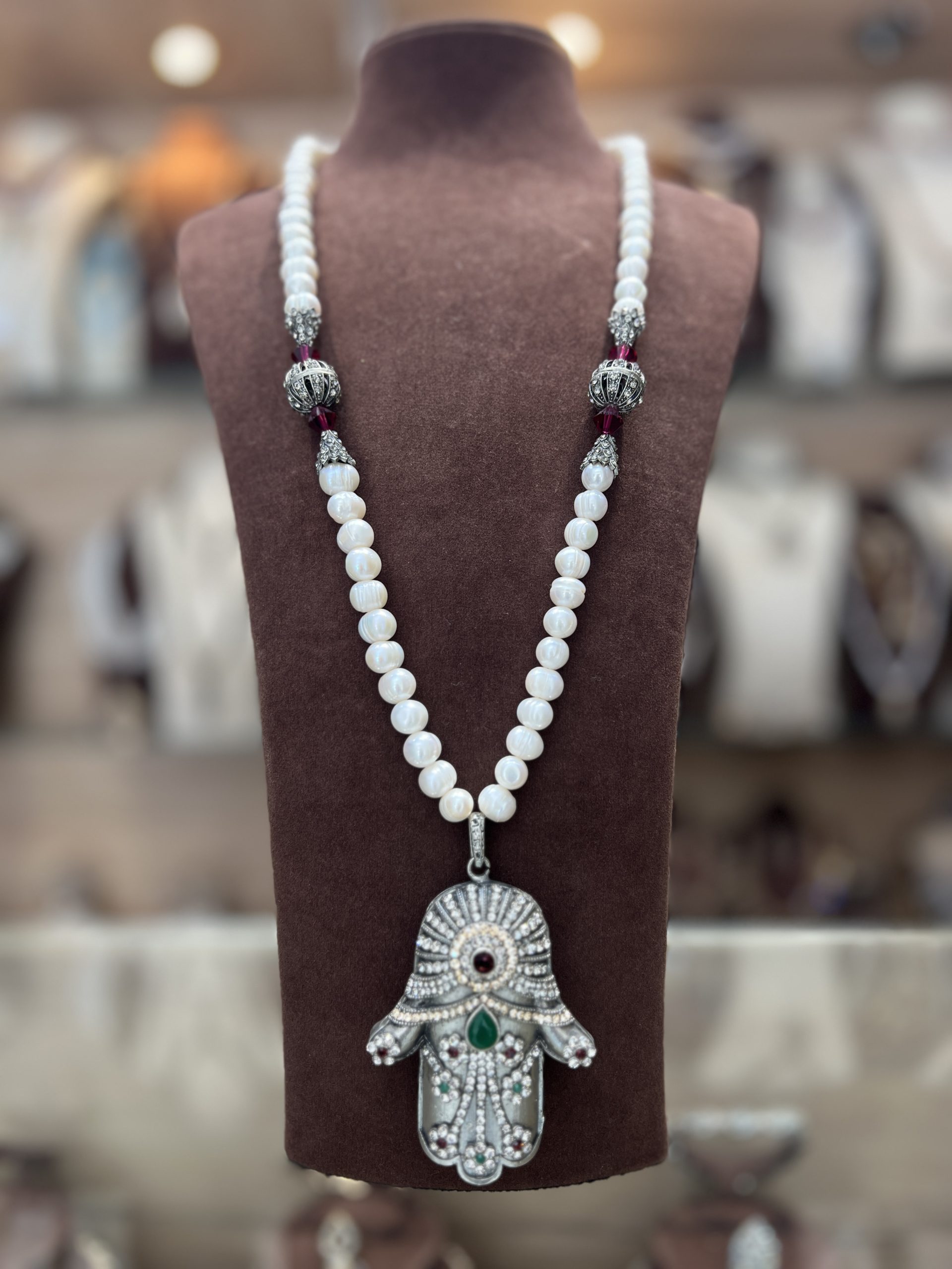 sautoir-khamssa-royale-perles-el-djohar Sautoir Khamssa Royale en perles El Djohar nacrées blanches avec boules argentées ciselées, cristaux bordeaux et pendentif Main de Fatma serti de zircons, émeraude et rubis