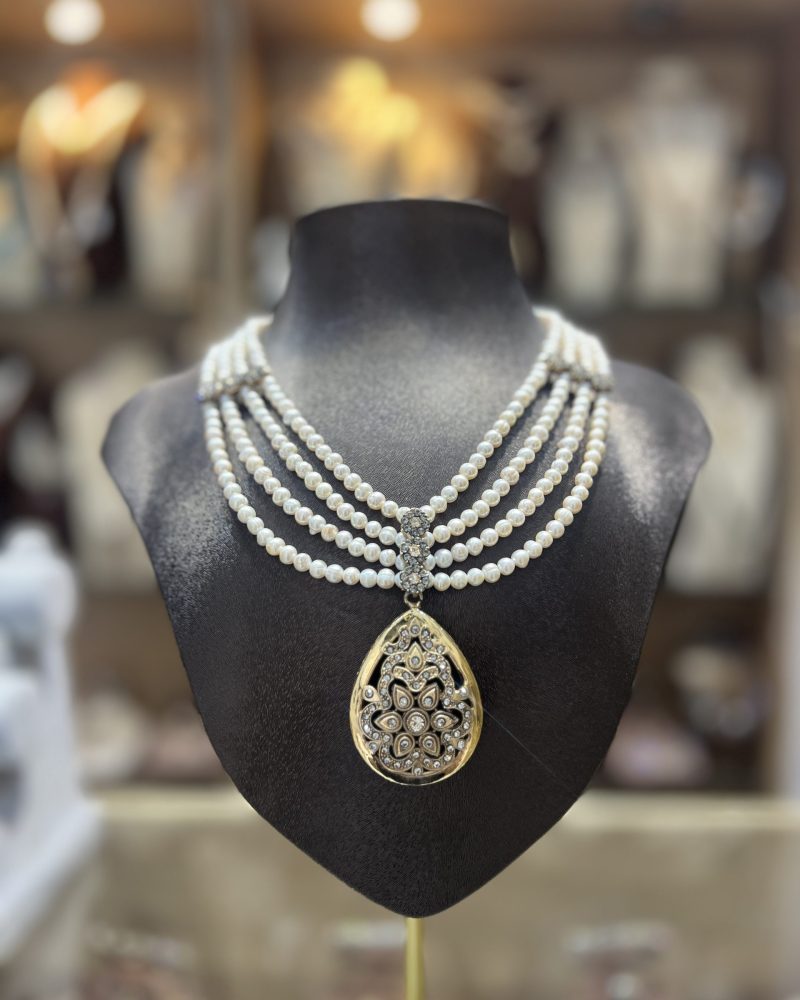Collier Mkhebel Shahrazed Doré à 4 rangs de perles El Djohar nacrées blanches avec barrette sertie et pendentif larme royale en filigrane floral